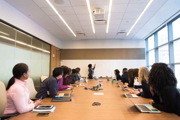 A group of professionals seated at a long table in a conference room